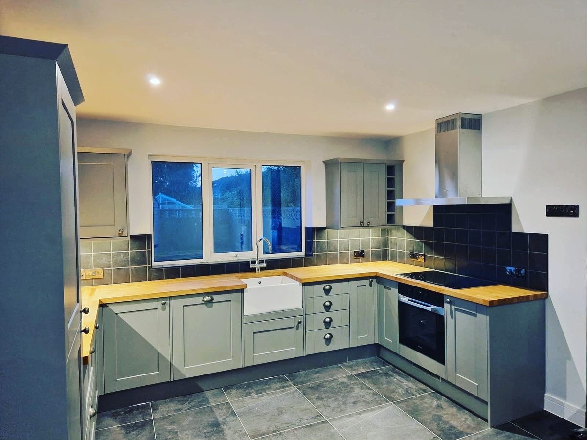 Shaker kitchen with oak worktops, a butler sink and blue metro tiling