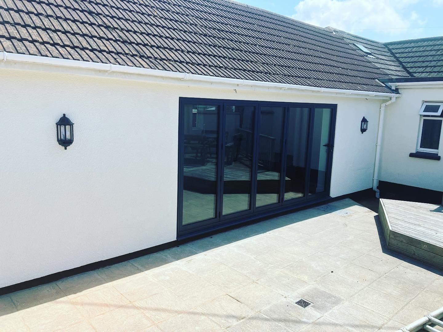 Rendered house extension with a long run of black bi-fold doors opening onto a patio