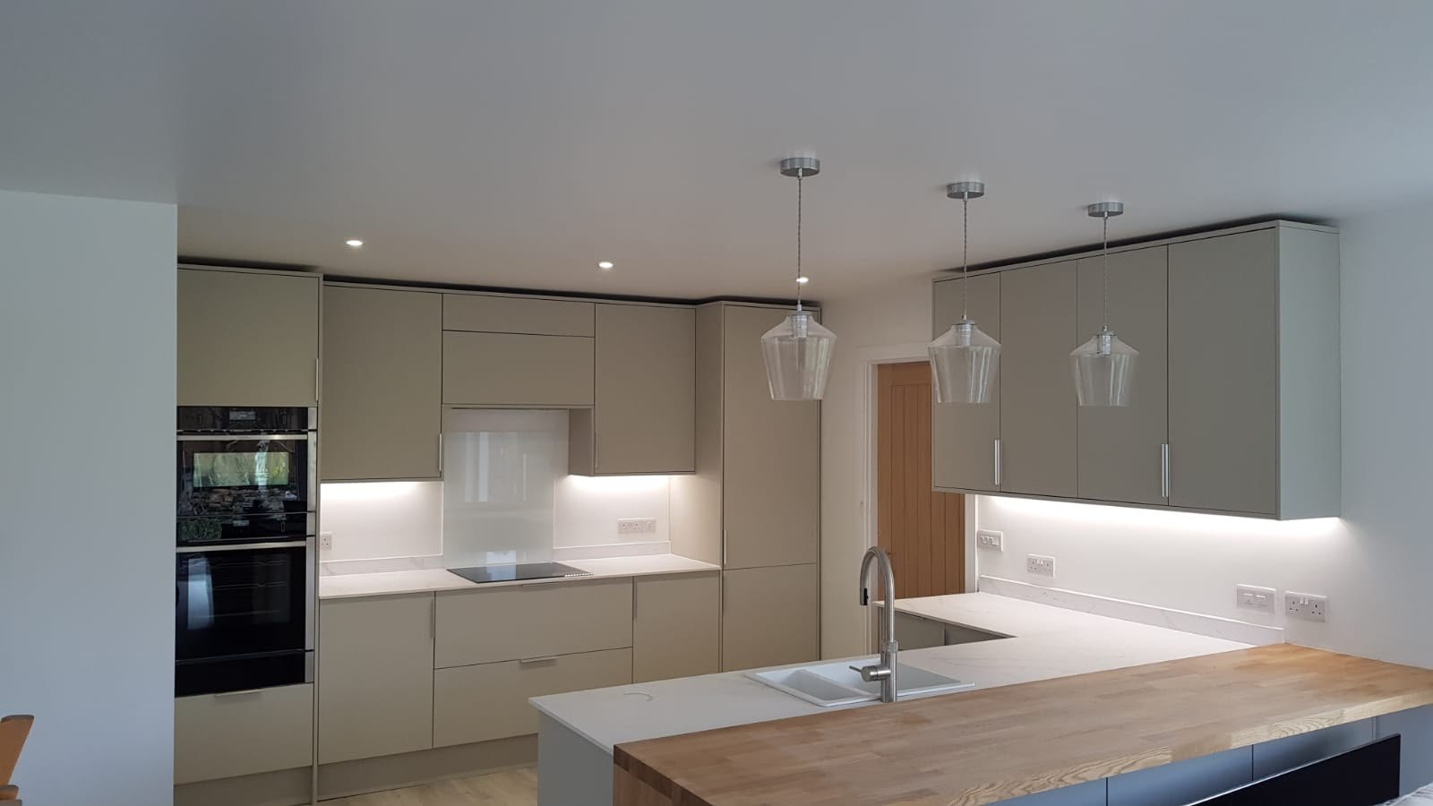 Fitted kitchen with cashmere units, pendant lighting and an oak breakfast bar