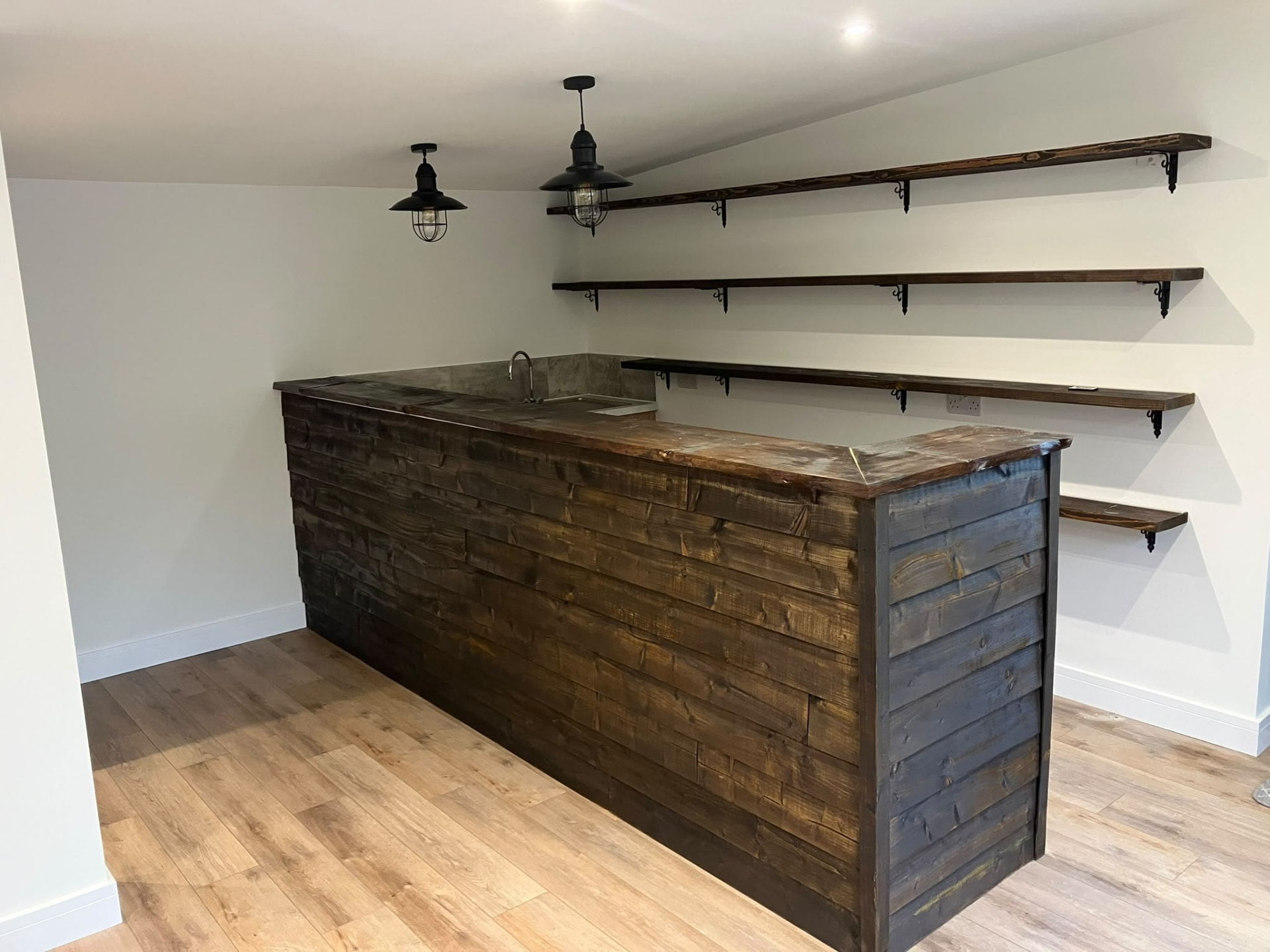 Bespoke joinery: a dark timber home bar with matching floating shelves built by our carpenters