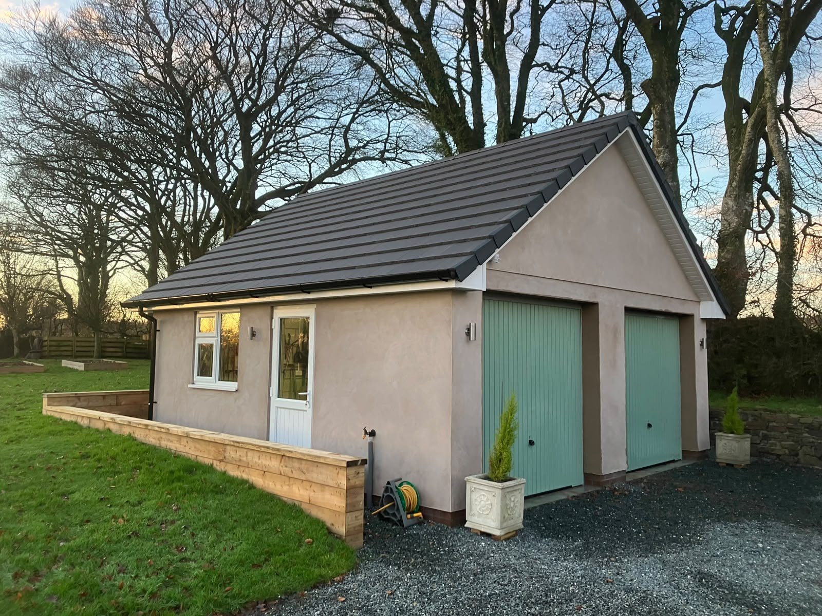Detached double garage with timber doors and a slate roof completed in North Devon