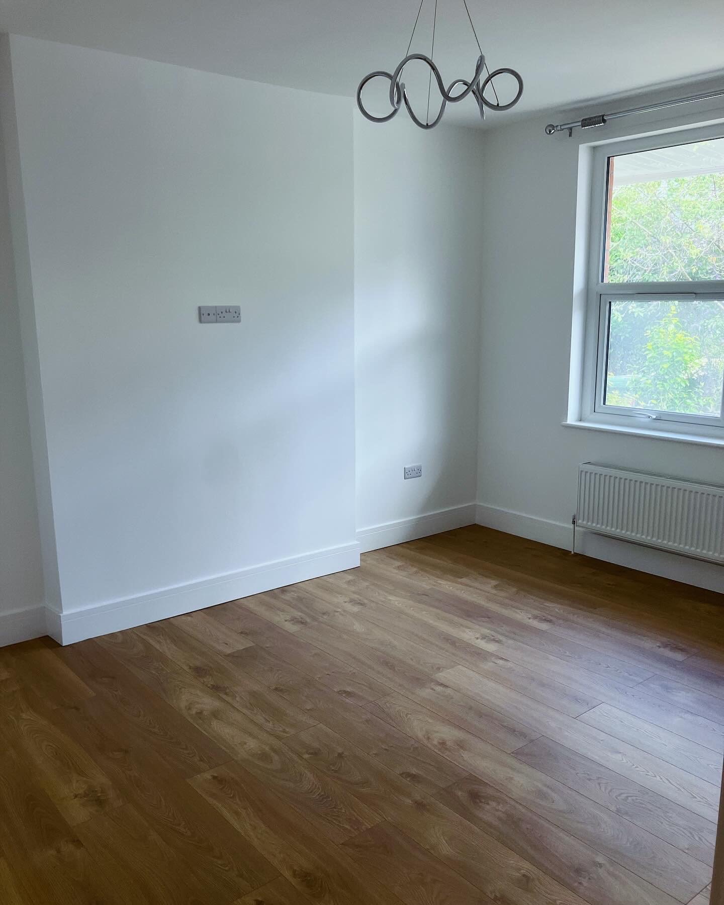 Redecorated bedroom after renovation with new flooring, skirting and window