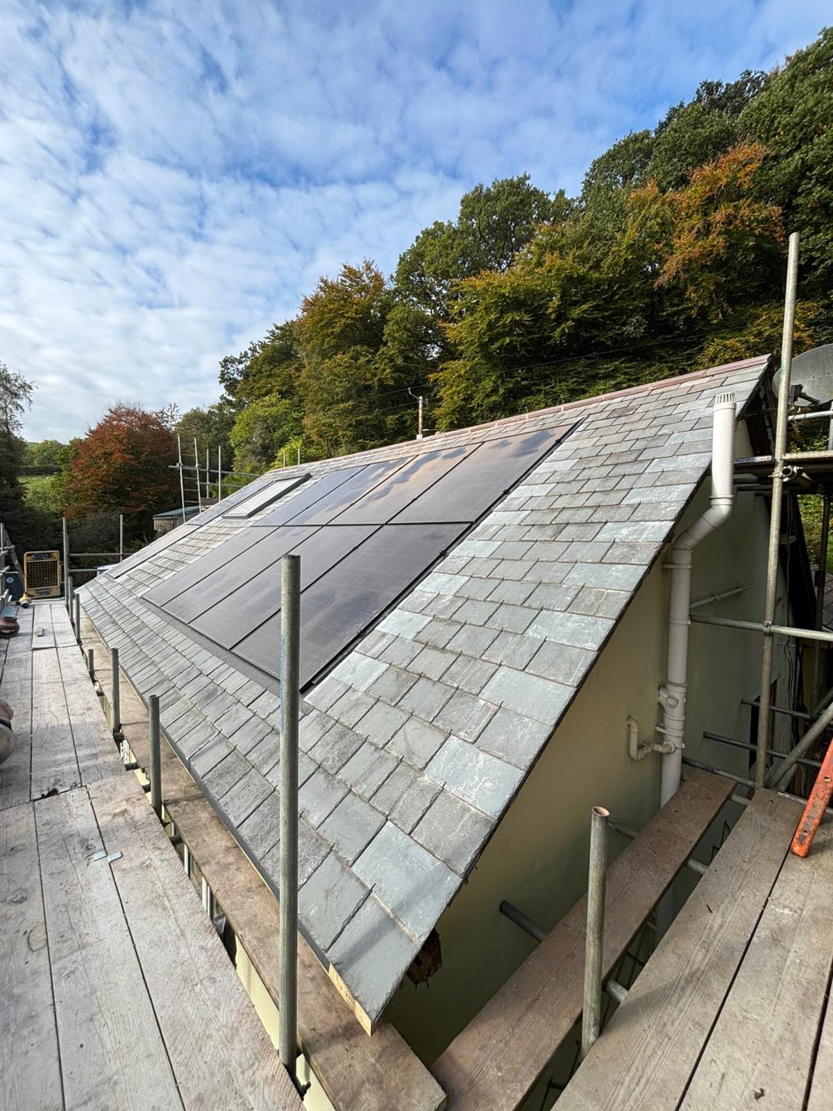Slate roof with integrated solar panels and scaffolding during building work