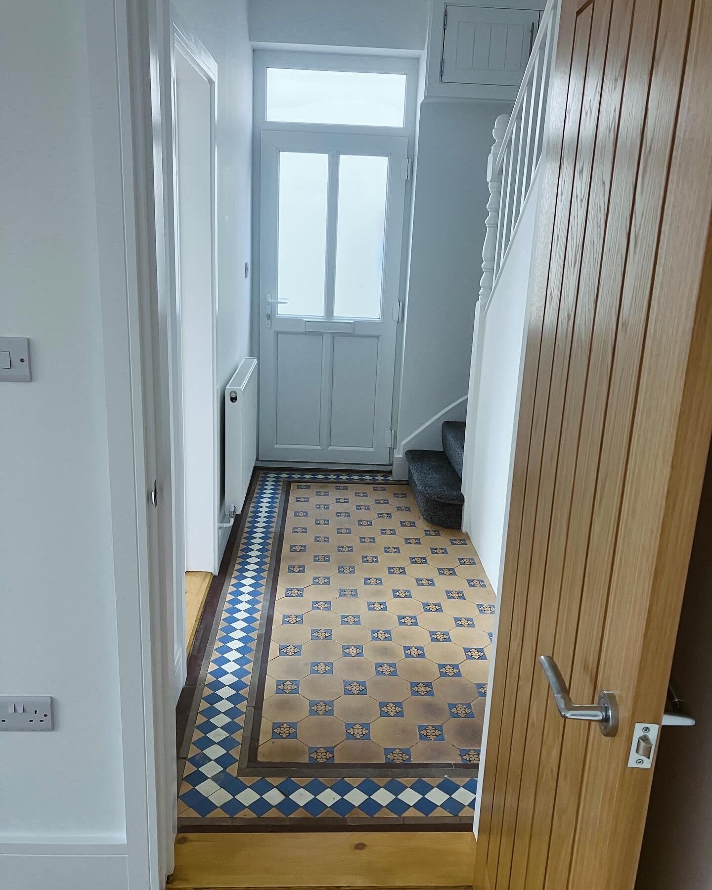 Traditional geometric floor tiling laid in a Victorian hallway with a patterned border