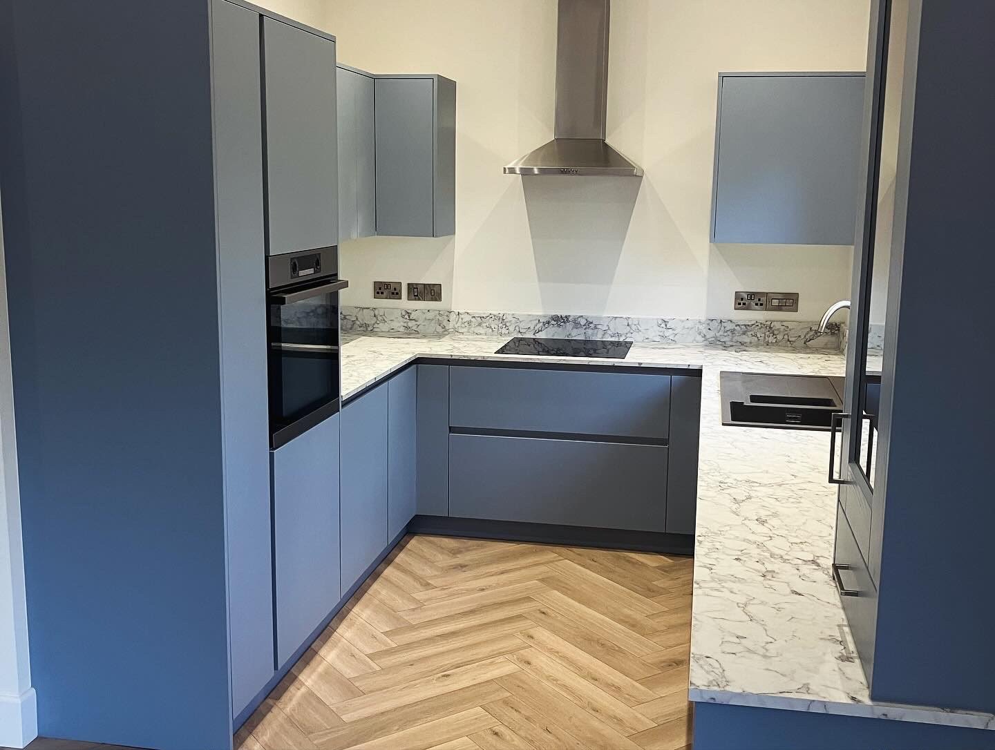 Grey-blue kitchen with marble-patterned worktops and matching upstands