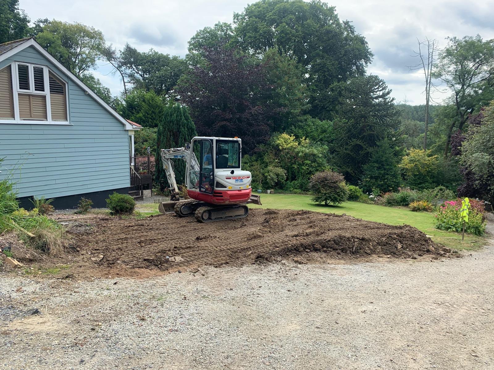 Excavator digging out spoil during groundworks on a domestic site