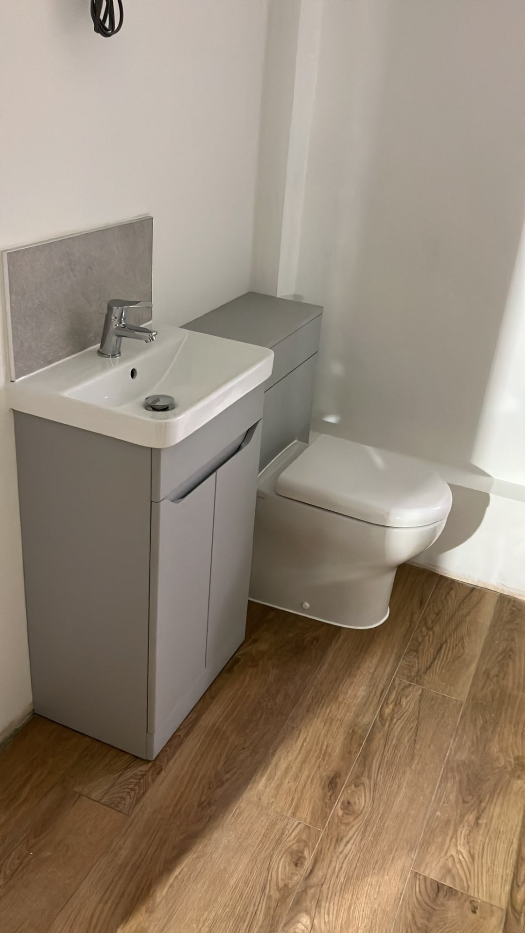 Slim grey vanity unit and concealed cistern fitted in a compact bathroom
