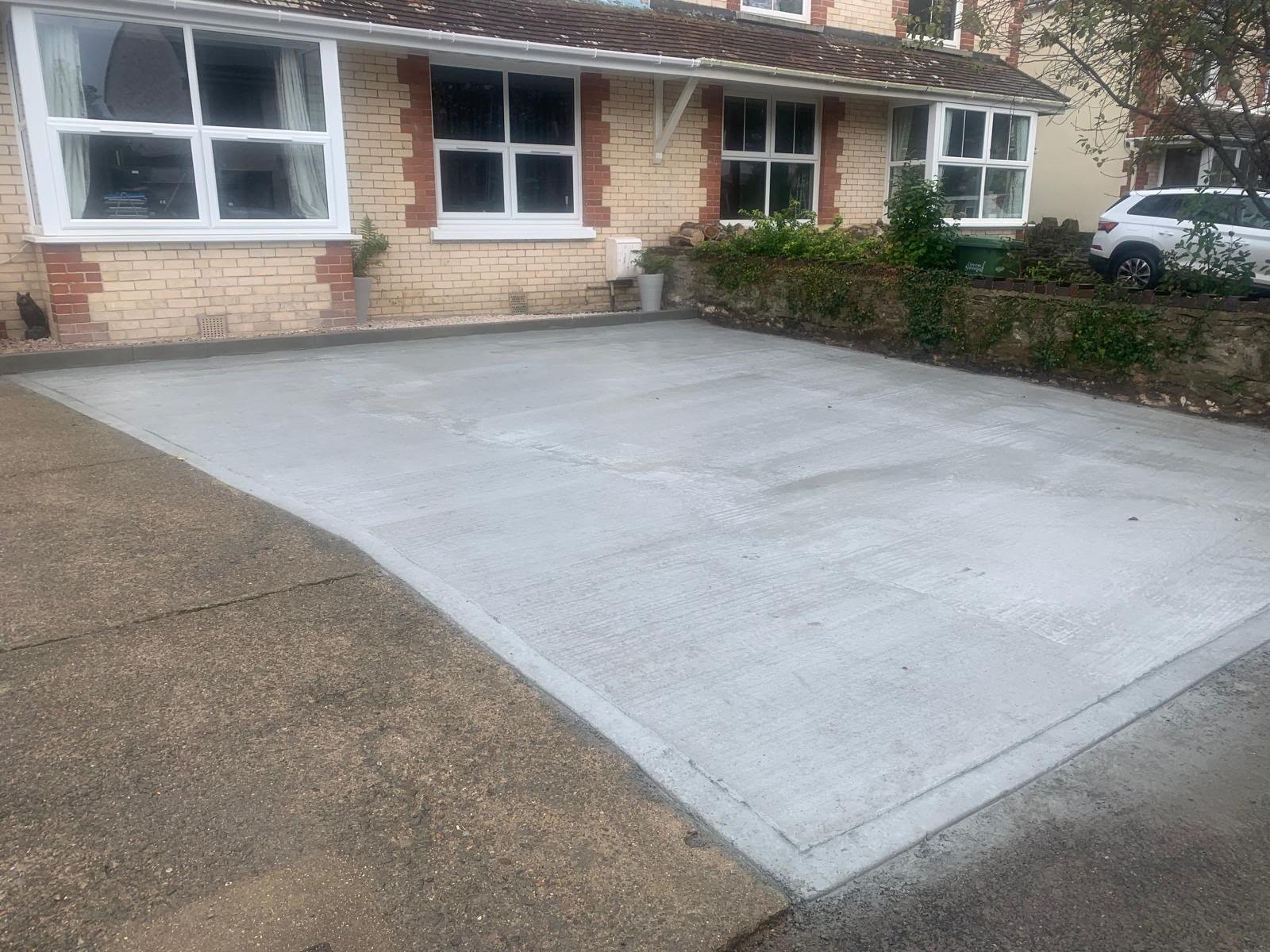 Newly poured concrete driveway laid in front of a brick house