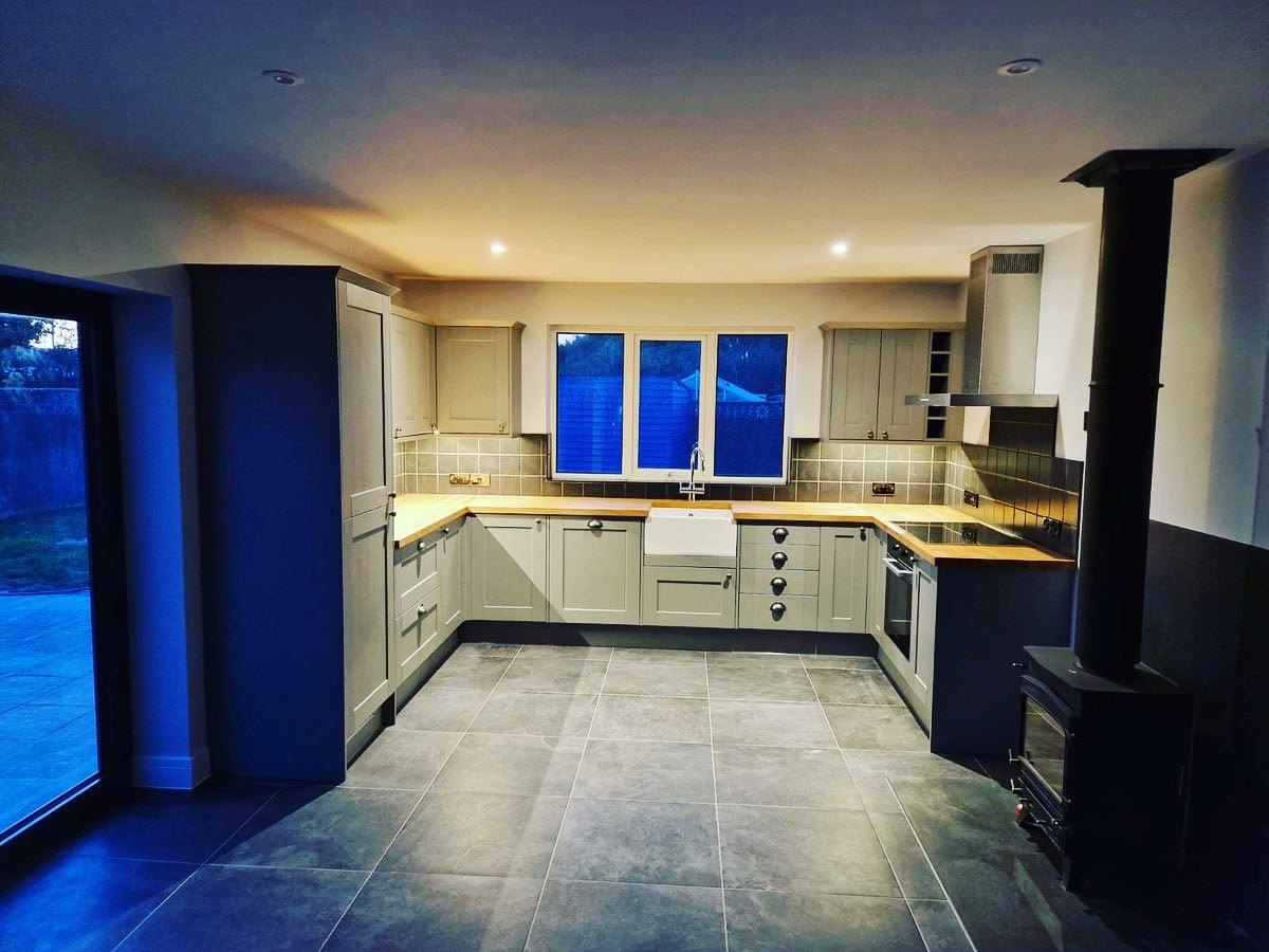 Open-plan shaker kitchen with oak worktops, a wood burner and tiled flooring