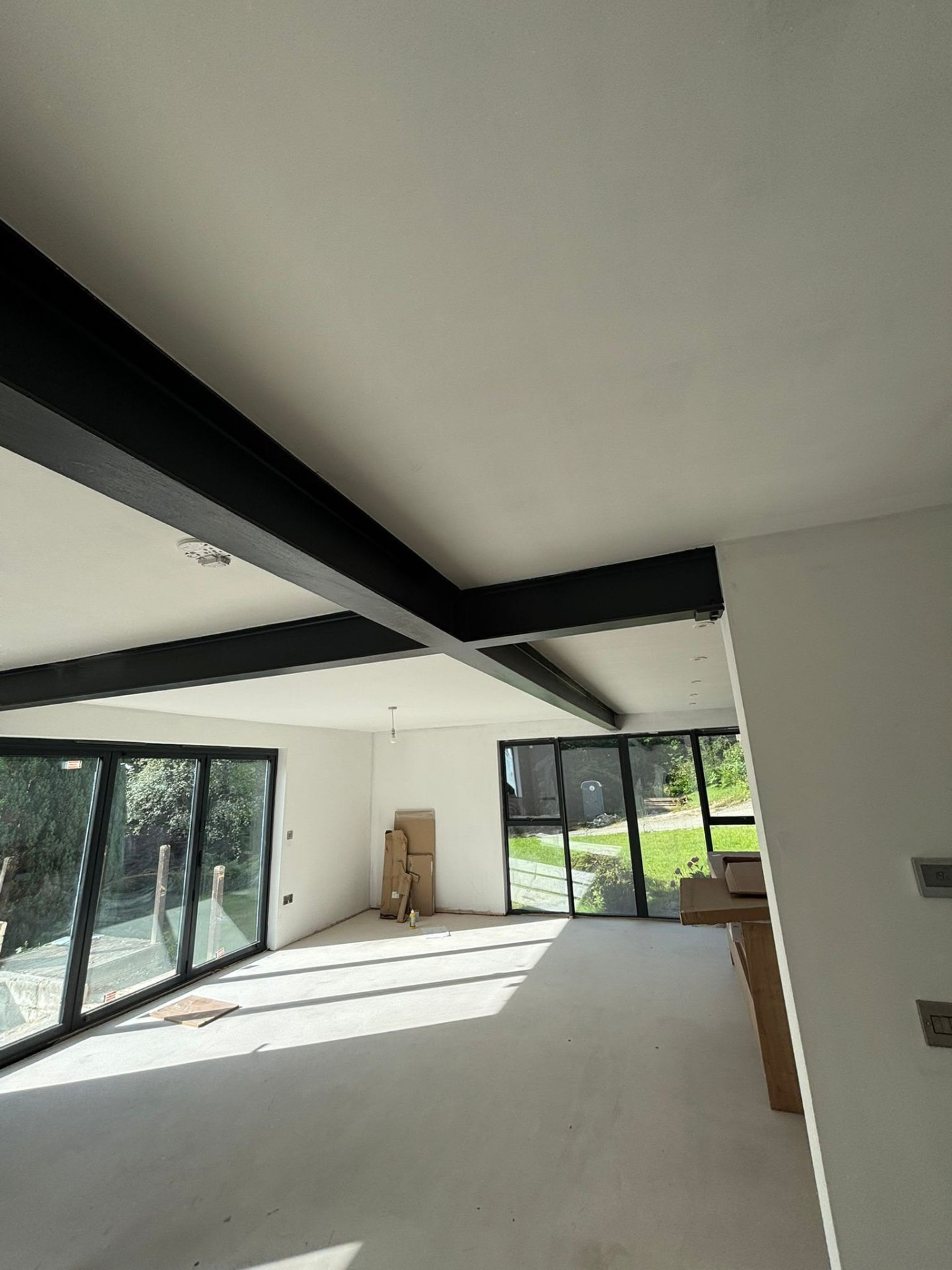 Structural steel beams installed to open up a ground floor with full-height glazing
