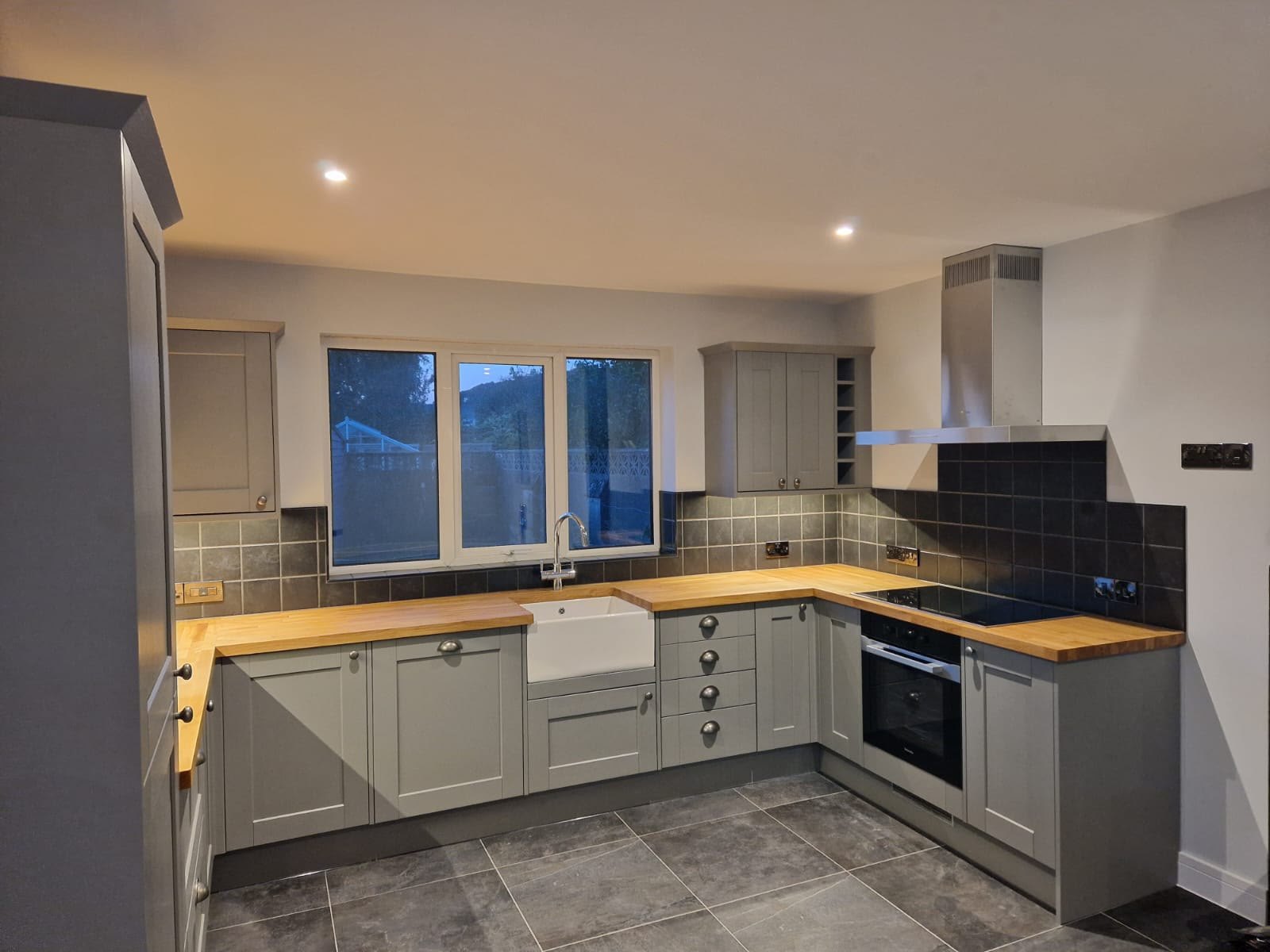 Shaker kitchen in grey with solid oak worktops, a butler sink and slate-effect floor tiles