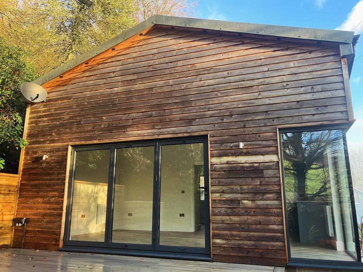 Timber-clad single-storey extension with black-framed sliding glass doors