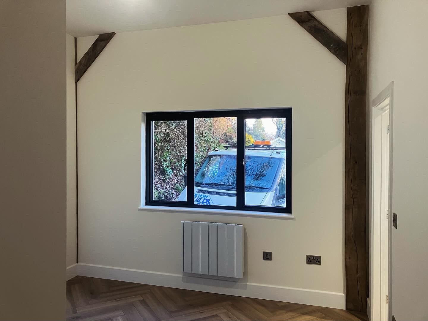 Extension interior with exposed vertical timber posts, white walls and dark window frames