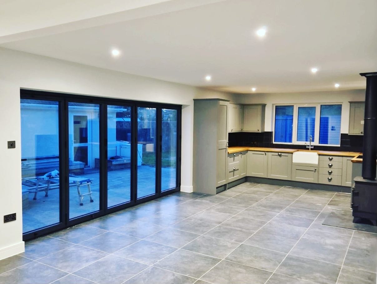 Large-format grey floor tiling laid through an open-plan kitchen extension with bi-fold doors