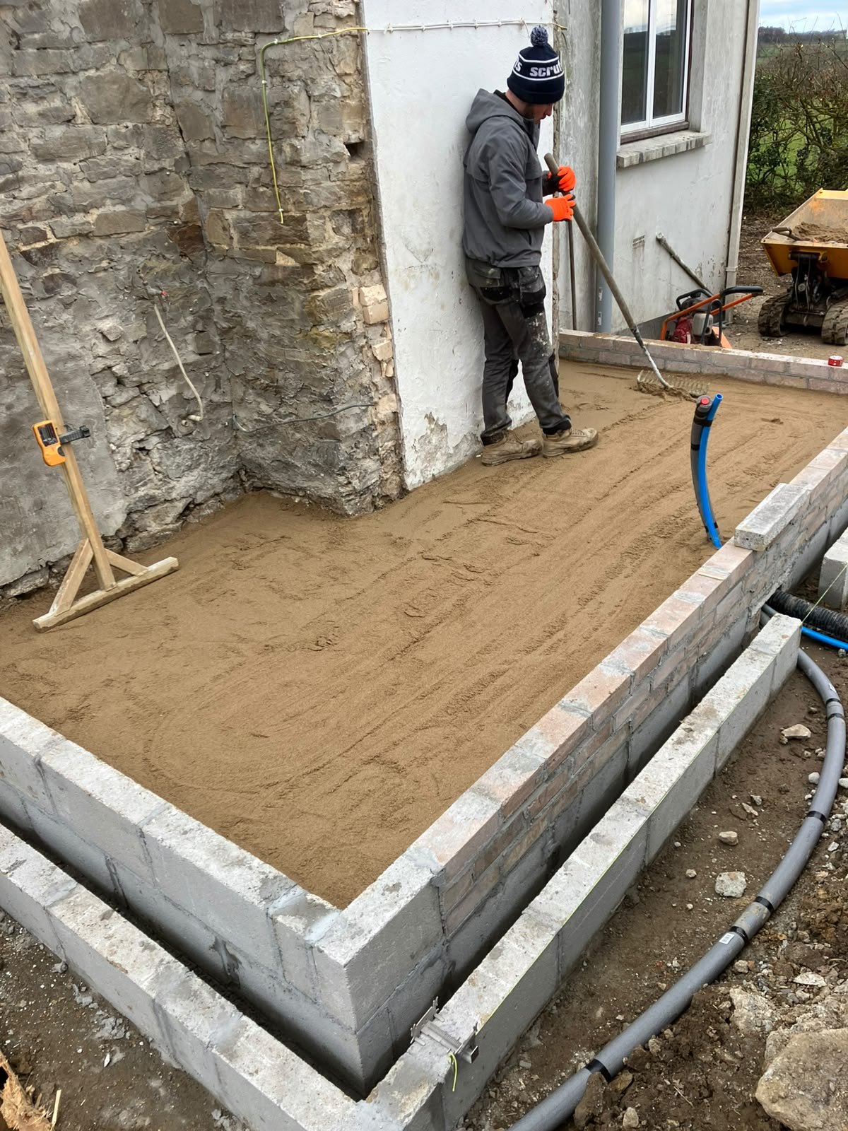 Levelling the sand base inside blockwork foundations before slab work